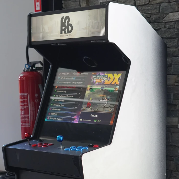 Borne d'arcade murale compacte de type "Pandora Box DX", écran LCD 720p affichant un menu de sélection de jeux rétro (Mortal Kombat 4, Street Fighter II, Metal Slug, Pac-Man, Tetris)