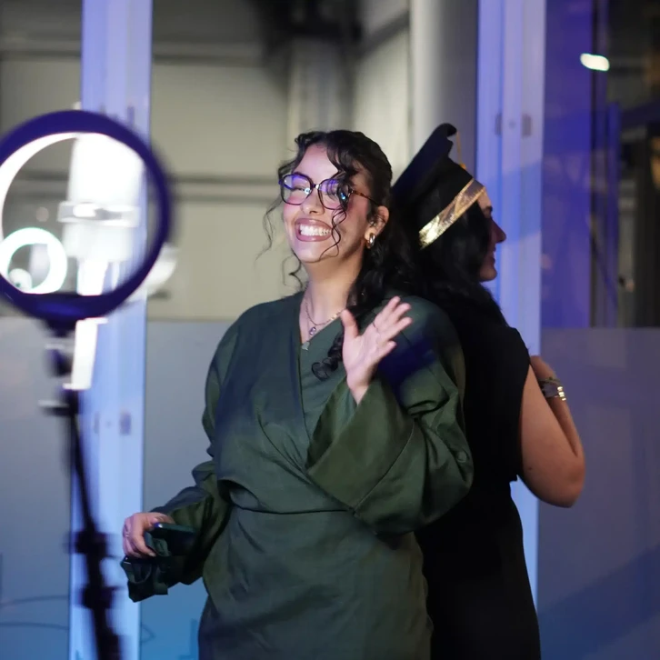 Événement nocturne en intérieur, deux femmes souriantes près d'un ring light LED circulaire sur trépied