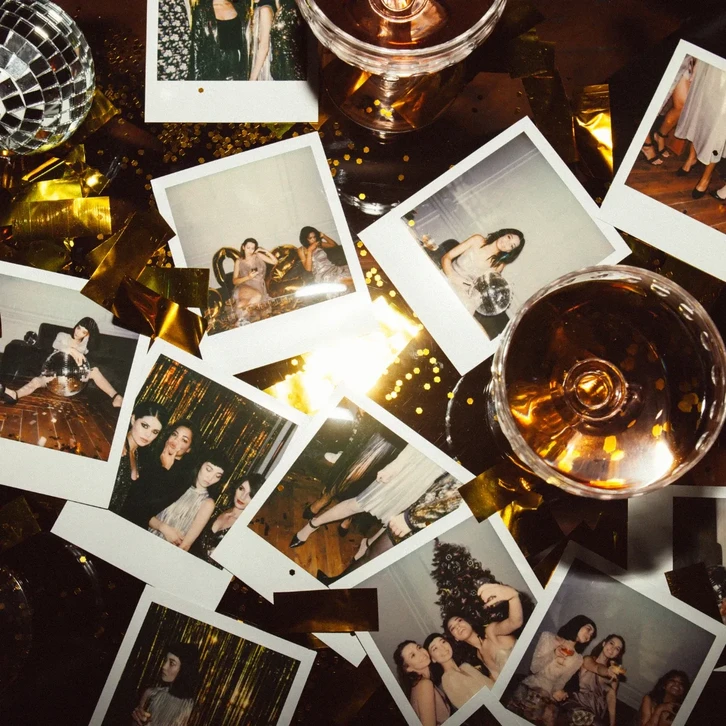 Polaroïds éparpillés sur une surface sombre avec confettis et guirlandes dorées, représentant des femmes élégantes en tenues de soirée lors d'une fête