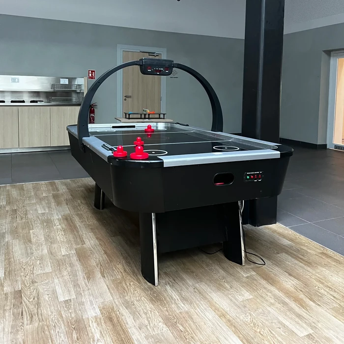 Table de air hockey noire avec arche décorative circulaire, dans une salle de loisirs intérieure